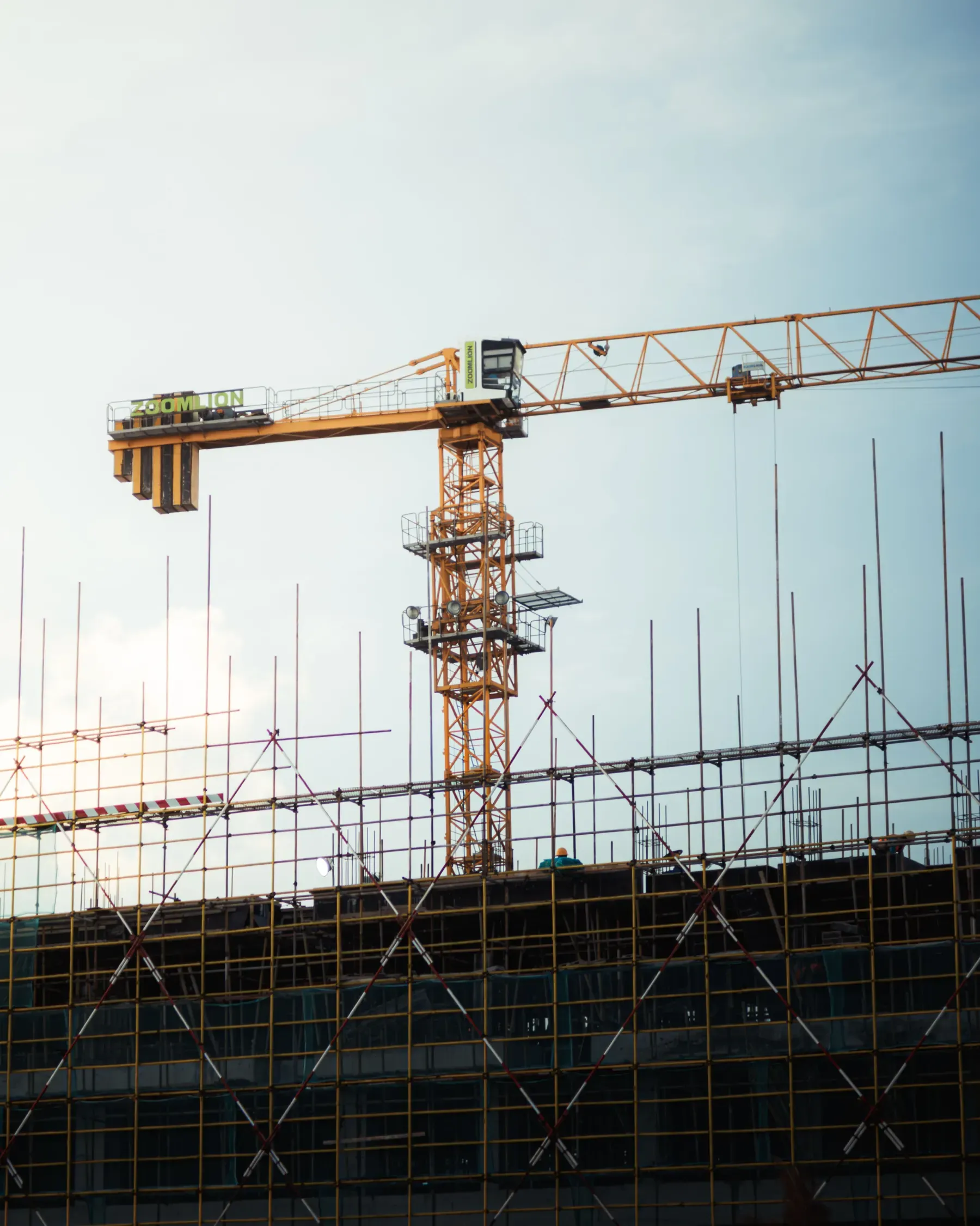 A tower crane above a scaffolded building under construction